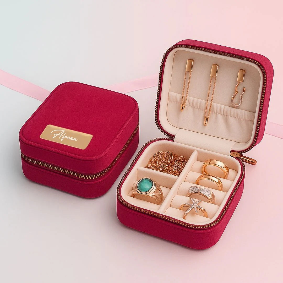 Red jewelry box with gold jewelry on a light pink background