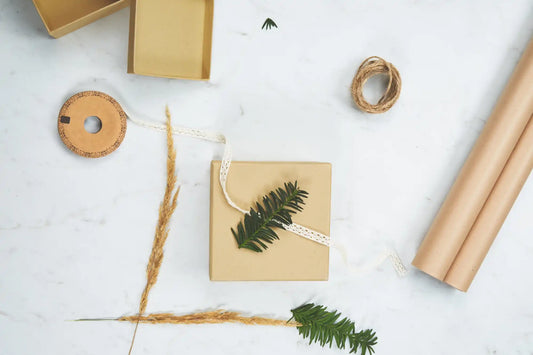 Small gift box with a green fern leaf tied on top using twine.