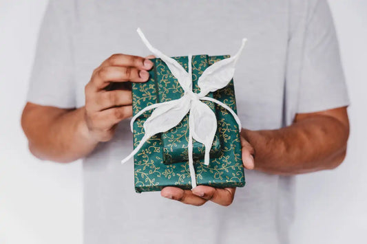 Gift wrapped in green floral paper with a white ribbon bow.