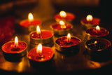 Group of lit red candles in small metal holders.