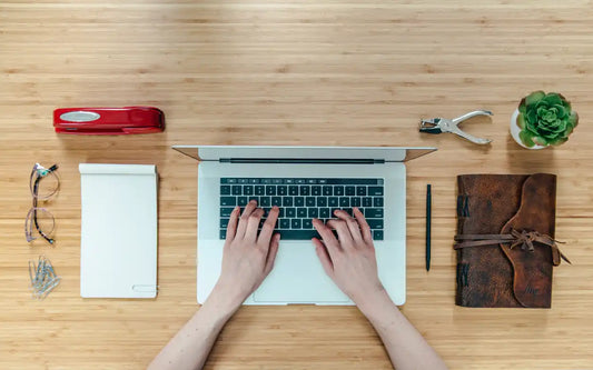 Laptop with hands typing on its keyboard.